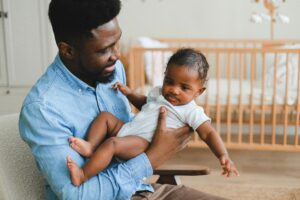A loving father holding his baby in a cozy, warm nursery. Capturing the essence of parent-child bonding and fatherhood.